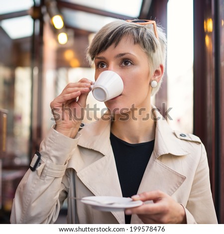 Young woman drinking coffee in a cafe in Paris, France. Shallow depth of field.