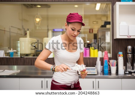 Young beautiful sales woman portrait preparing ice cream cup.