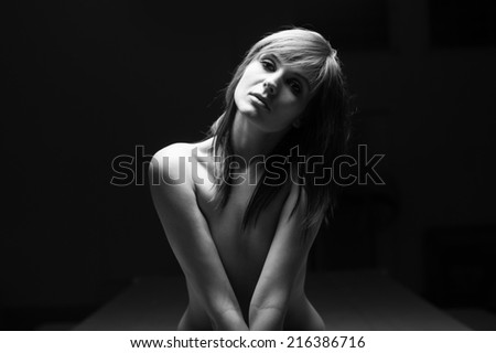 Young intimate woman beauty portrait against dark background. Black and white image.