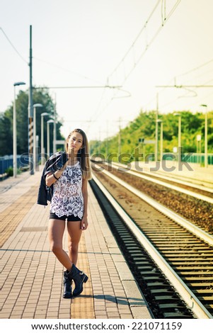 Fashion portrait of young woman outdoors in train station. Filtered image.