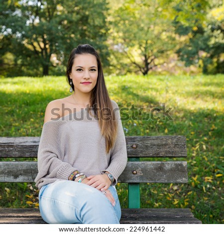 Beautiful young woman portrait with natural green background relaxing in a park.