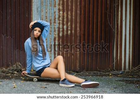 Full body teenager portrait with skateboard against old grunge rugged sheet.
