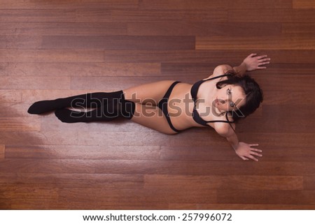 Sensual woman portrait laying on parquet floor with black underwear. Full body portrait.
