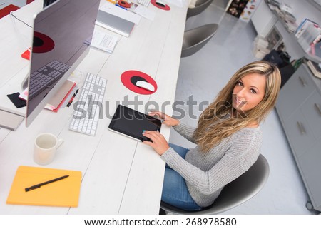 Young smiling woman portrait working with tablet in modern office.
