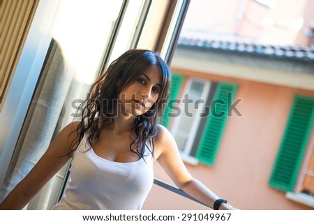 Portrait of sensual young woman at the window in hotel room. Shallow depth of field.