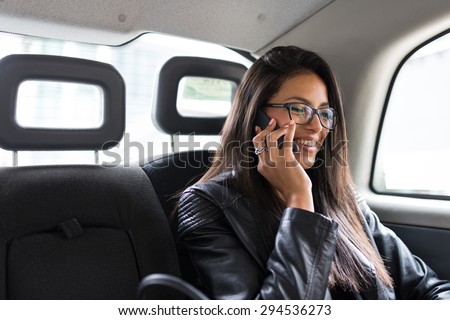 Young mixed race businesswoman portrait inside a taxi in Canary Wharf area in London talking at the phone.