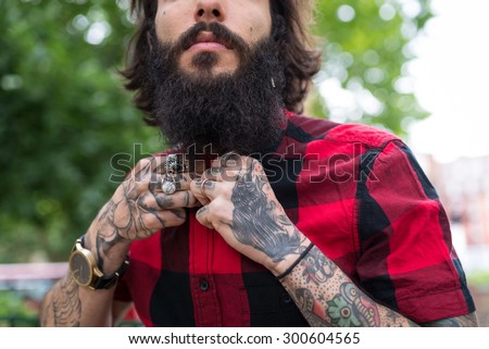 Hands close up of young tattooed man portrait in a park. Shoreditch borough, London. Hipster style.