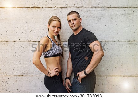 Athletic man and woman couple portrait against concrete background. Concept of happy couple enjoying fitness and healthy lifestyle - Vintage filtered look.