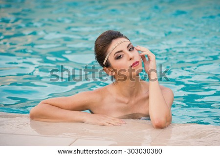 Sensual portrait of beautiful brunette woman in swimming pool. Filtered image.