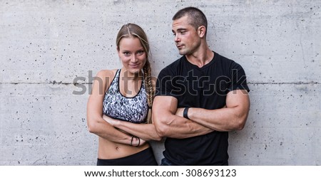 Athletic man and woman couple portrait against concrete background.