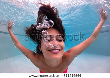 Happy underwater woman portrait in swimming pool.