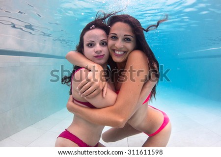 Girlfriends underwater portrait in swimming pool.