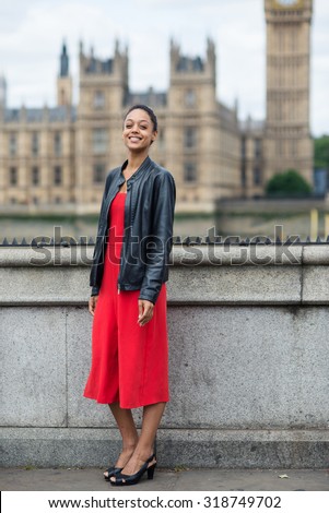 Young smiling businesswoman full body portrait outdoors in London with Big Ben as background.