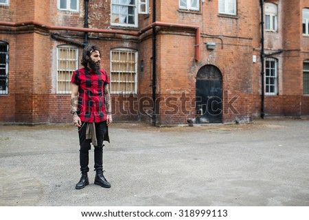 Full body portrait of young tattooed man standing in Shoreditch borough. London, UK. Hipster style.