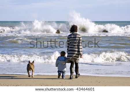 Mother and son with dog on the beach.