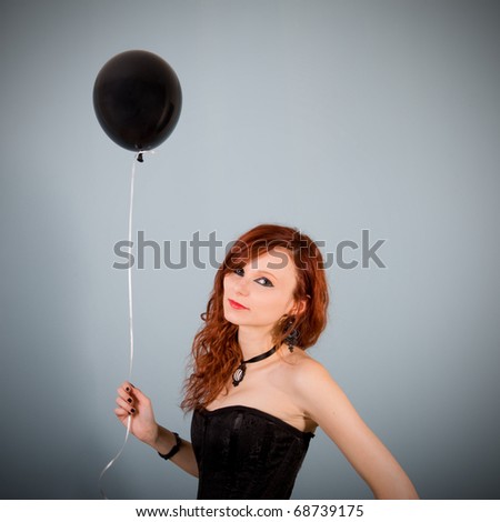 Portrait of beautiful red caucasian girl with black balloon.