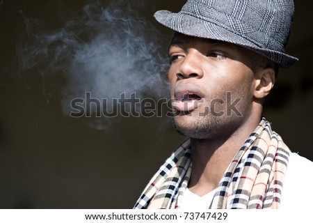 Black man smoking cigar portrait with hat.