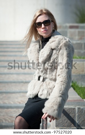 Young attractive business woman with fur in front of modern business offices center.