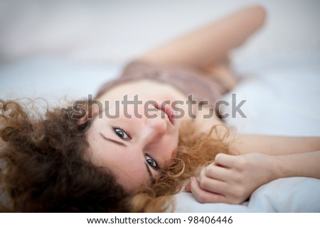 Portrait of a sensual young woman lying on bed. Shallow depth of field.