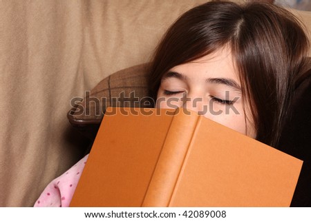 tired little girl sleeps with a book