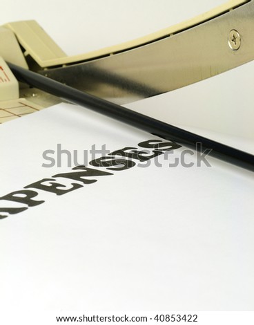 Expenses banner under the blade of a paper cutter