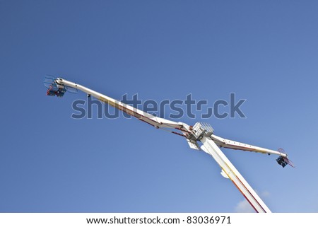 exciting fairground ride in mid air against blue sky