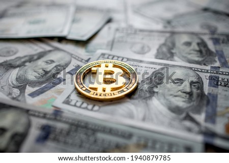 Golden symbolic coin Bitcoin on banknotes of one hundred dollars. Exchange bitcoin cash for a dollars. Cryptocurrency on US dollar bills. Digital modern method of payment. Savings, investments concept