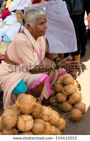 MAPUSA, INDIA - MARCH 15: Elderly woman coconut seller on the market  in Mapusa on March 15, 2013, Mapusa, India. In India often sell coconut to earn a small cash income.
