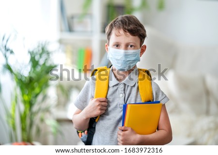 Little schoolboy wearing mask during corona virus and flu outbreak. llness protection for kids. Mask for coronavirus prevention. School kid coughing. Little boy breathes through mask, going to school.