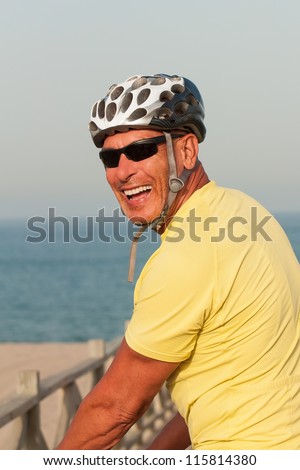 Portrait of a happy smiling active older man with a cycling helmet on a summer evening