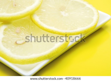 Sliced lemon on white square plate on yellow