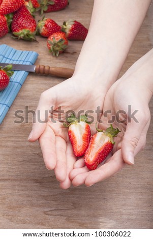 studio-shot of woman`s hands showing a halved fresh strawberry