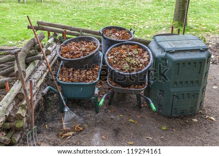 garden work during autumn season.  garden tools , wheelbarrow and buckets full with dry autumn leaves