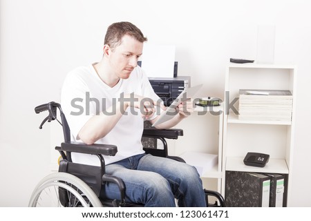 Young man on wheelchair working in a Office, using a tablet computer
