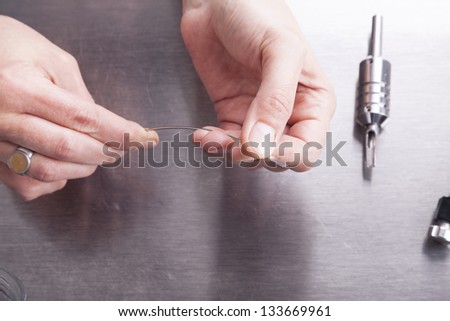 tattoo artist at work.  preparing the needle and the tattoo machine.