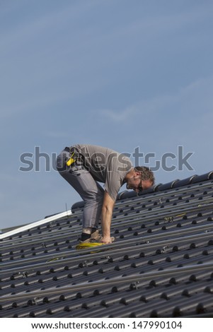 worker preparing the roof to install alternative energy photovoltaic solar panels.