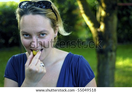 Woman bites in a fresh yellow plum