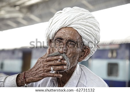 Portrait of a smoking Rajasthani Indian man with turban and a typical Rajasthani style beard.