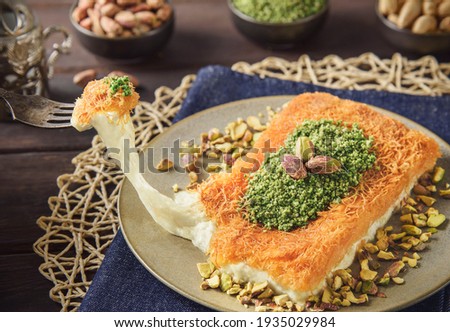 Arabic Cuisine; Traditional Middle Eastern Cheese Kunafa Dessert. A delicious pastry consisting of soft melty cheese and shredded phyllo dough. Served with sugar syrup and crushed pistachio.