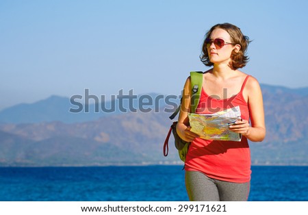 Young woman tourist walks on the seashore  reading the map. Traveling along Asia, freedom and active lifestyle concept