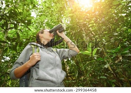 hiker watching through binoculars wild birds in the jungle. Bird watching tours