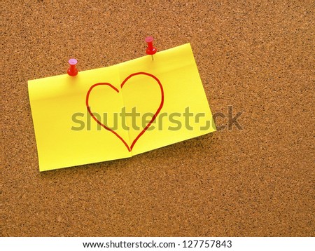 heart shape drawn on two post it notes put together on office cork board