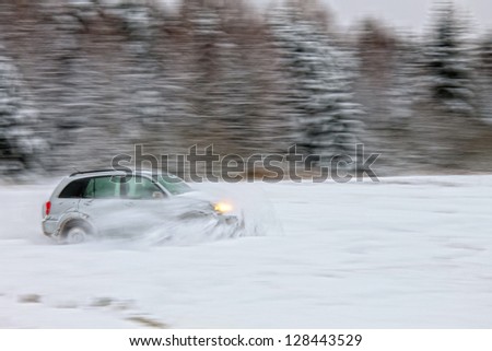 Car driving on snow, motion blurred focus on car