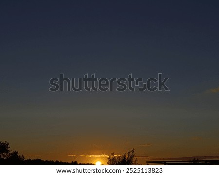Golden sun touches the distant tree tops as it sinks to the horizon.