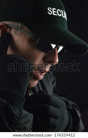 Close-up of a security guard reporting the situation into his microphone.