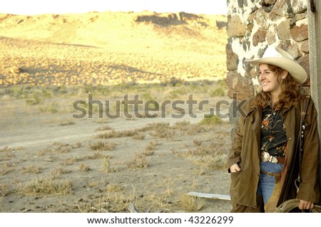 happy cowgirl at sunset wearing a long coat with hat and rope