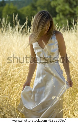 Bride in a golden field in summer afternoon