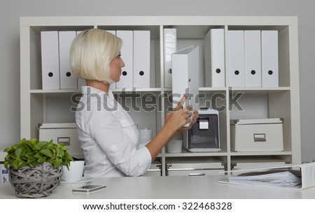 secretary puts back a folder from her desk into the cabinet