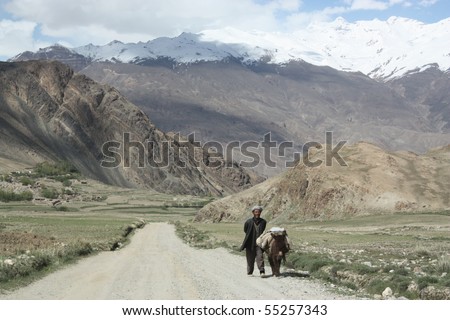 ISHKASHIM, AFGHANISTAN - MAY 28: Man and his donkey walk along newly constructed road on 28th May, 2010, Ishkashim, Afghanistan