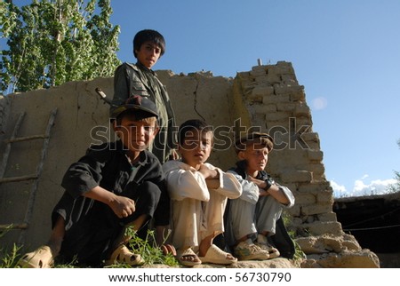 BAHARAK, AFGHANISTAN - JUNE 2: Four young school friends sit on top of a wall having finished their first day at a newly built school on June 2, 2010 in Baharak, Afghanistan